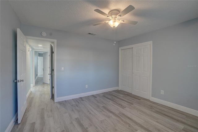 unfurnished bedroom with a textured ceiling, light hardwood / wood-style floors, a closet, and ceiling fan