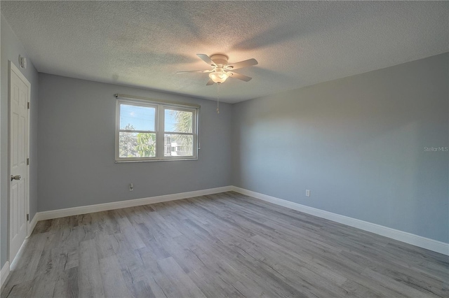 unfurnished room featuring ceiling fan, light hardwood / wood-style floors, and a textured ceiling