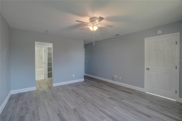 spare room featuring ceiling fan, light hardwood / wood-style flooring, and a textured ceiling