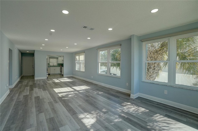 unfurnished living room with a textured ceiling and dark hardwood / wood-style floors