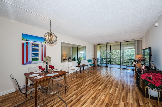 dining room featuring wood-type flooring, a textured ceiling, and a wall of windows