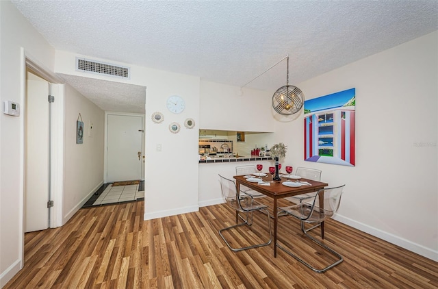 dining room featuring wood-type flooring and a textured ceiling