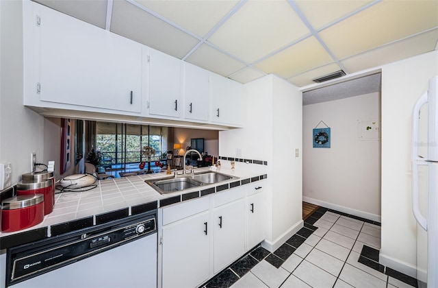 kitchen featuring sink, white appliances, light tile patterned floors, white cabinetry, and tile countertops