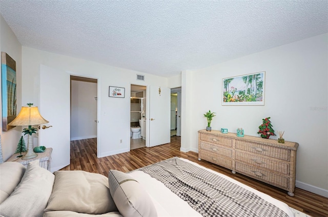 bedroom featuring dark hardwood / wood-style floors, a textured ceiling, and ensuite bathroom