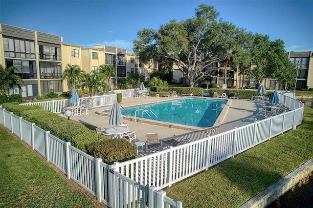 community pool with a lawn, a patio, and fence