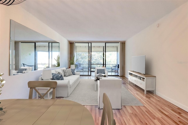 living room with floor to ceiling windows, baseboards, and light wood-type flooring