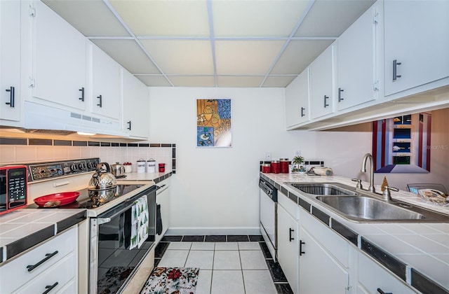 kitchen featuring tasteful backsplash, range with electric cooktop, tile counters, white dishwasher, and a sink