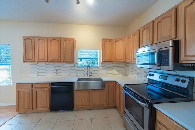 kitchen with light tile patterned flooring, appliances with stainless steel finishes, a wealth of natural light, and sink