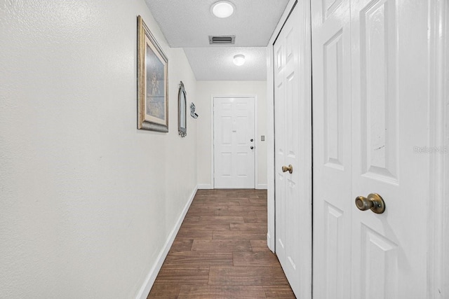 corridor featuring dark wood-type flooring and a textured ceiling