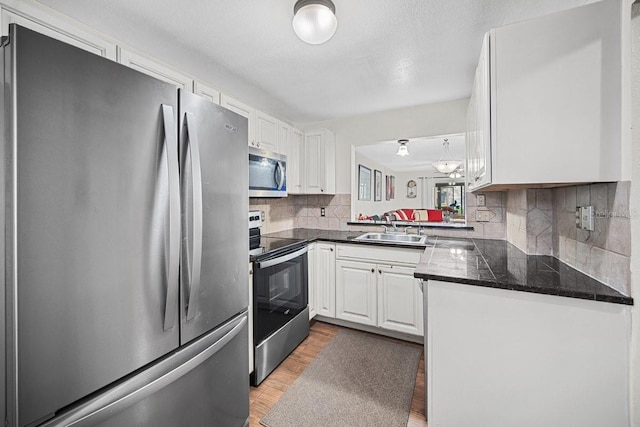 kitchen featuring sink, light hardwood / wood-style flooring, decorative backsplash, white cabinetry, and stainless steel appliances