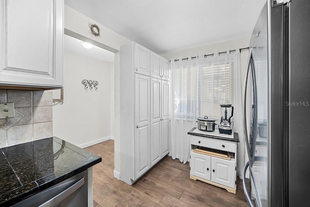 kitchen featuring tasteful backsplash, white cabinetry, dark wood-type flooring, and stainless steel appliances