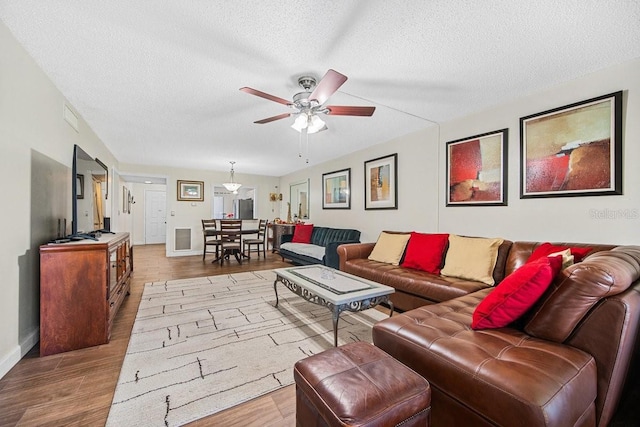 living room featuring hardwood / wood-style flooring, ceiling fan, and a textured ceiling