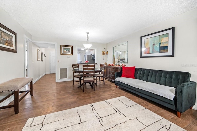 living room with a textured ceiling and dark hardwood / wood-style flooring