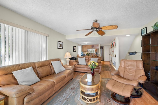 living room featuring hardwood / wood-style floors, a textured ceiling, and ceiling fan