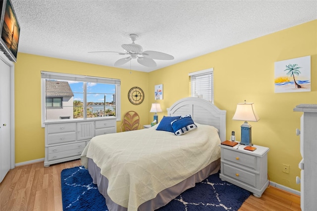 bedroom featuring a closet, ceiling fan, light hardwood / wood-style floors, and multiple windows