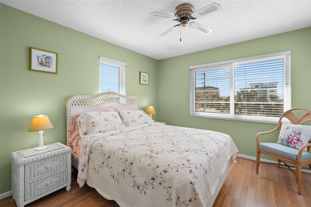 bedroom with light wood-type flooring, a textured ceiling, and ceiling fan