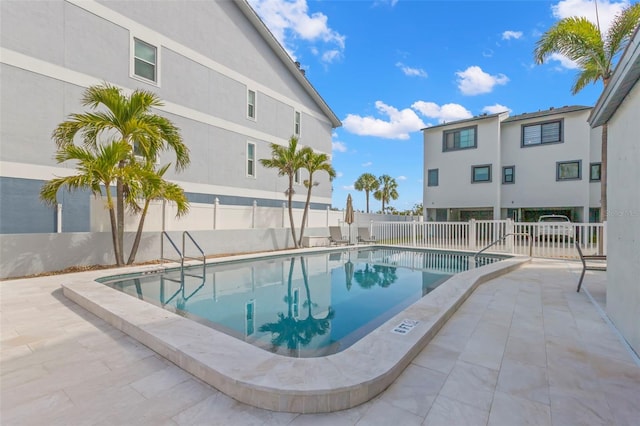 community pool with a patio and fence