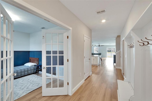 hallway with light hardwood / wood-style floors and french doors