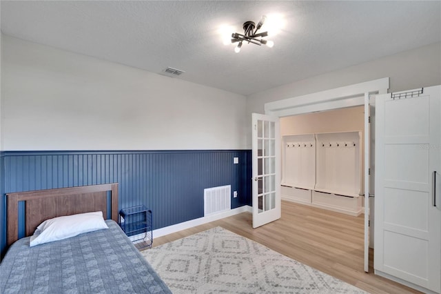 bedroom with wood-type flooring, a textured ceiling, and french doors