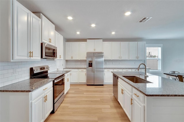 kitchen with white cabinetry, sink, stainless steel appliances, light hardwood / wood-style floors, and a kitchen island with sink