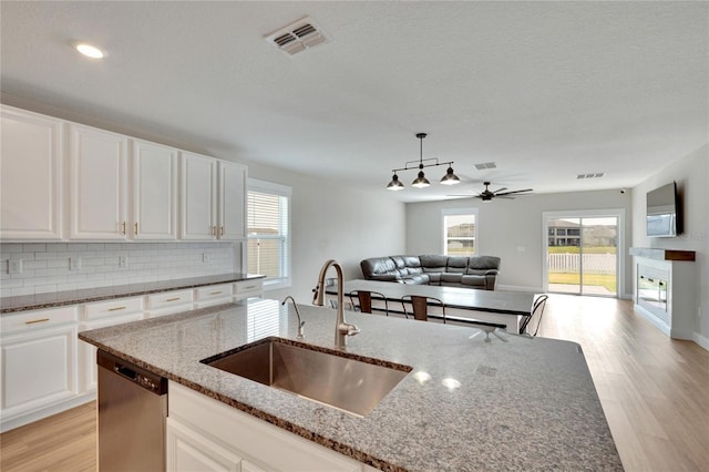 kitchen featuring dishwasher, dark stone countertops, white cabinetry, and sink