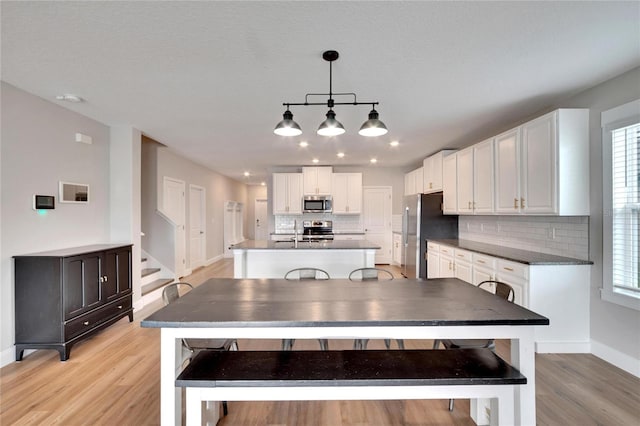 kitchen with white cabinets, a healthy amount of sunlight, stainless steel appliances, and hanging light fixtures