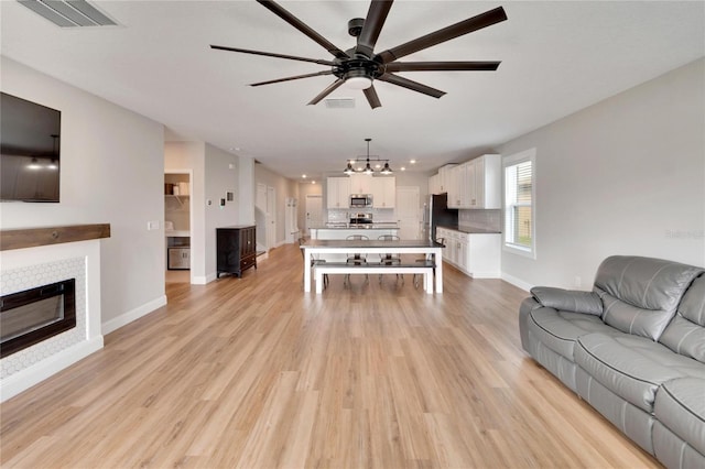 living room featuring a tile fireplace, light hardwood / wood-style flooring, and ceiling fan