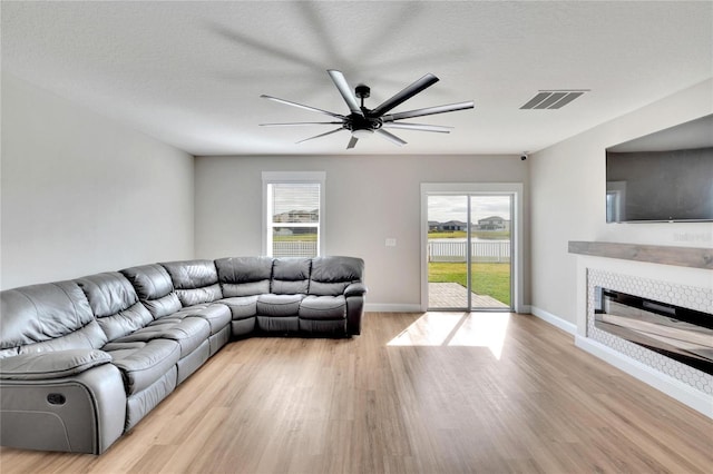 unfurnished living room featuring a fireplace, a healthy amount of sunlight, a textured ceiling, and light wood-type flooring