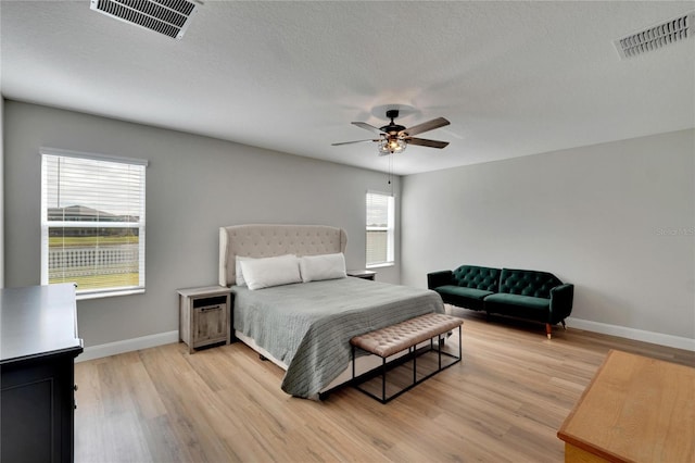 bedroom with a textured ceiling, light hardwood / wood-style floors, and ceiling fan