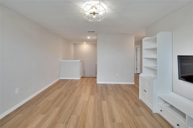 unfurnished living room with a textured ceiling and light hardwood / wood-style floors