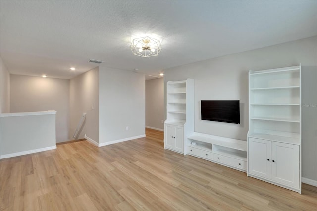 unfurnished living room featuring light hardwood / wood-style floors and a textured ceiling