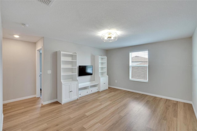 unfurnished living room with a textured ceiling and light hardwood / wood-style flooring