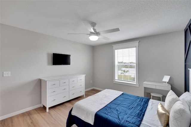 bedroom featuring ceiling fan, light hardwood / wood-style floors, and a textured ceiling