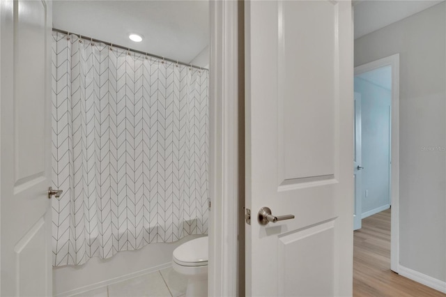 bathroom featuring hardwood / wood-style floors, shower / bath combination with curtain, and toilet