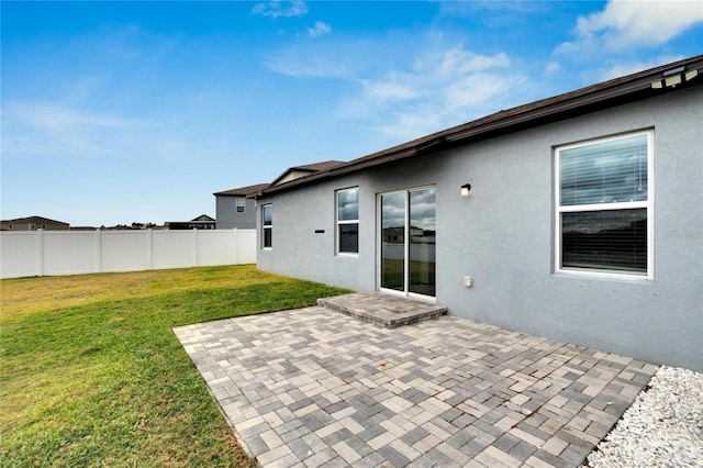 back of property with a yard and a patio