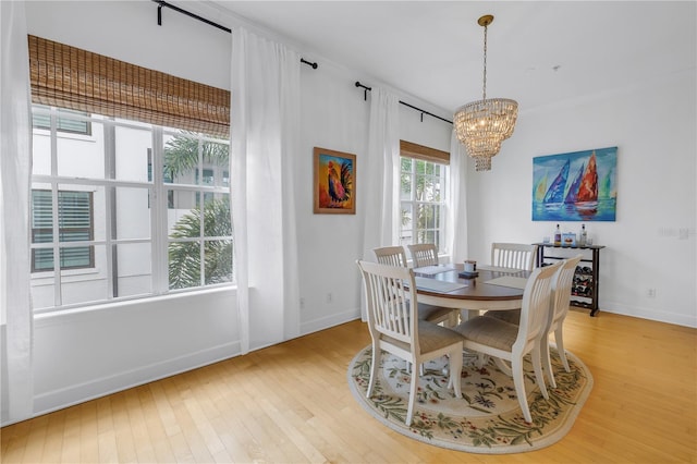 dining area with light wood-type flooring and a notable chandelier