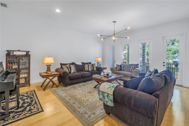 living room with a notable chandelier, a healthy amount of sunlight, and light hardwood / wood-style flooring