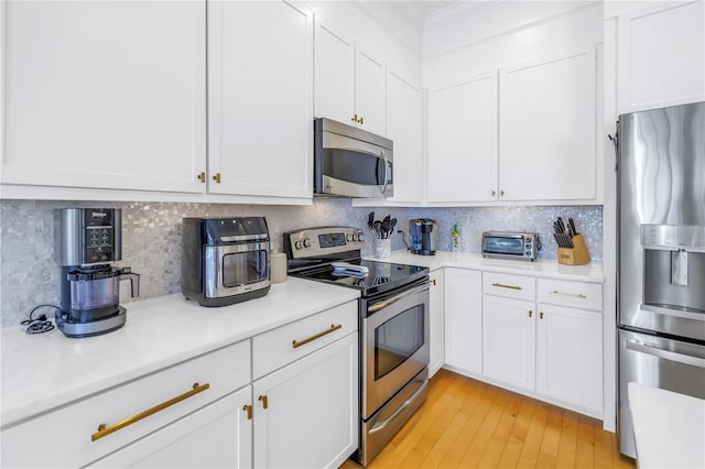 kitchen with white cabinets, light wood-type flooring, backsplash, and appliances with stainless steel finishes