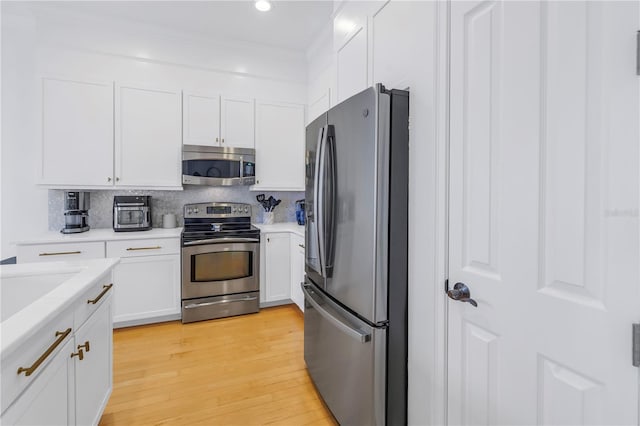 kitchen featuring decorative backsplash, light hardwood / wood-style floors, white cabinetry, and appliances with stainless steel finishes