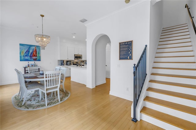 dining room with light hardwood / wood-style floors, sink, crown molding, and a chandelier