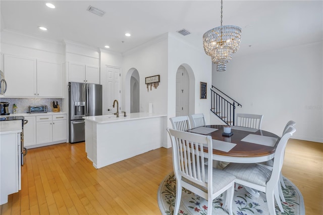 dining area with crown molding, light hardwood / wood-style flooring, and a chandelier