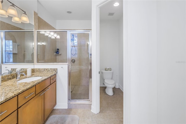 bathroom featuring tile patterned flooring, vanity, a shower with door, and toilet