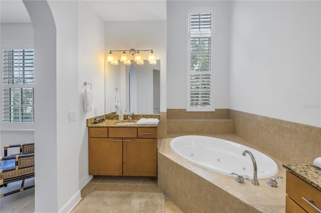 bathroom with tile patterned floors, vanity, and a relaxing tiled tub