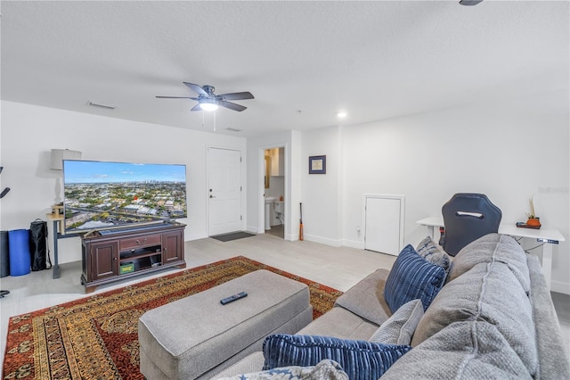 living room featuring ceiling fan and a textured ceiling