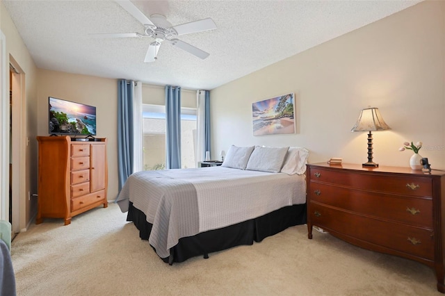 carpeted bedroom with ceiling fan and a textured ceiling