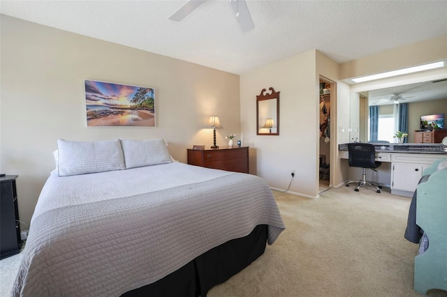 carpeted bedroom with a walk in closet, ceiling fan, a closet, and a textured ceiling