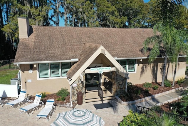 2740 Highlands Blvd Unit D, Palm Harbor, FL 34684 - view of front facade featuring stucco siding, a shingled roof, and a chimney