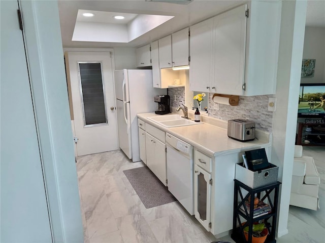 kitchen featuring backsplash, white appliances, a raised ceiling, sink, and white cabinetry