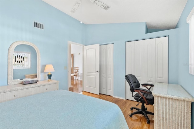 bedroom featuring multiple closets, ceiling fan, high vaulted ceiling, and light hardwood / wood-style floors