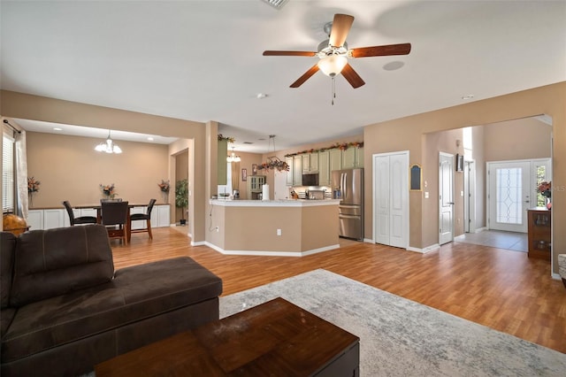 living room featuring ceiling fan with notable chandelier and light hardwood / wood-style floors